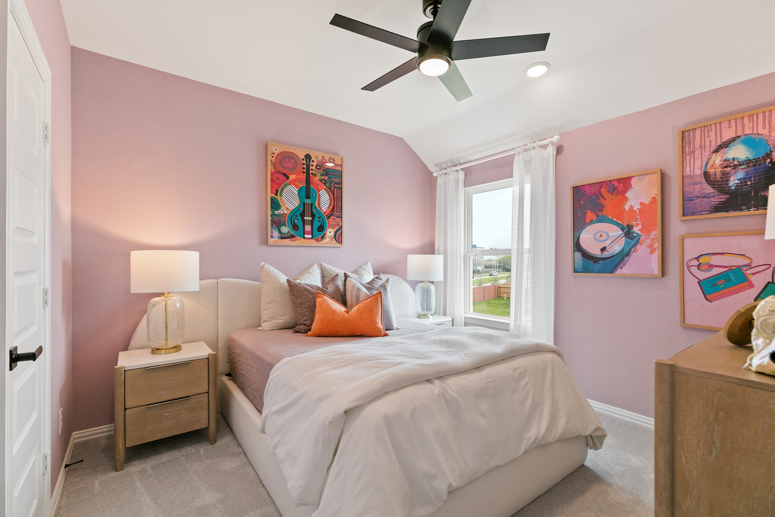 Elegant Bedroom with Pastel Décor and Modern Touches in Park at Eldridge Bedroom features pastel pink walls, modern ceiling fan, large window, unique artwork. Park at Eldridge, Texas.